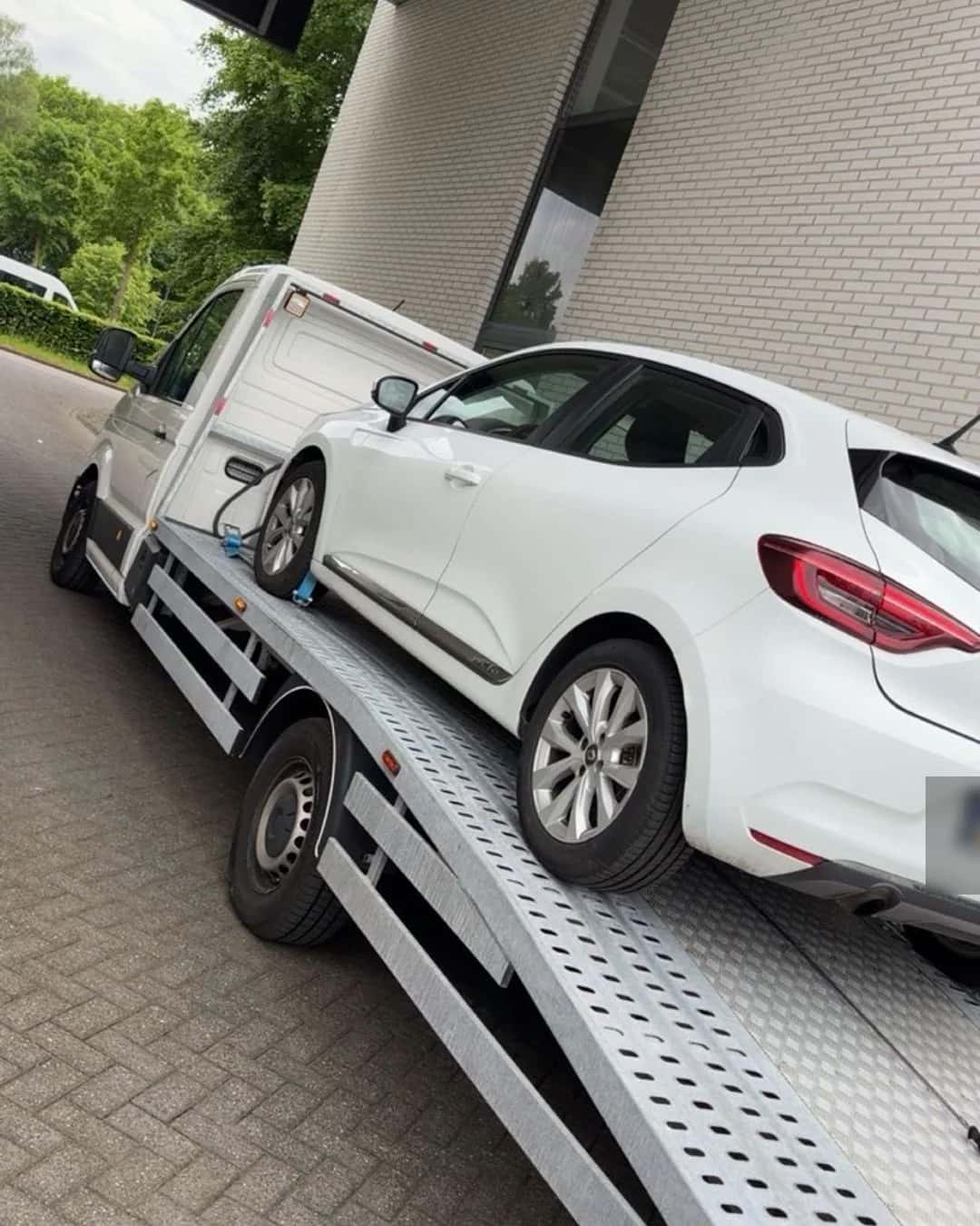 Witte personenauto geladen voor autotransport op afspraak