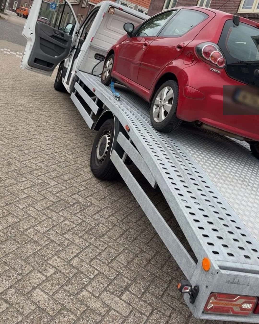 Rode personenauto op de oprijwagen voor regionaal vervoer